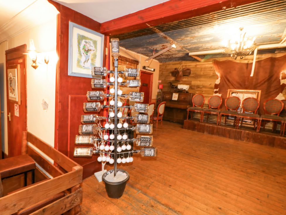 An indoor room with wooden floor and walls featuring chairs on a small stage and a tree made of bottles and white balls at Bear Claw Lodge Castlerock