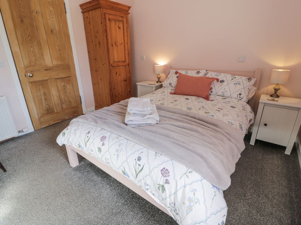 A bedroom with a bed covered in floral bedding and a pink pillow at Morton Mains Steading Cottage Near Thornhill