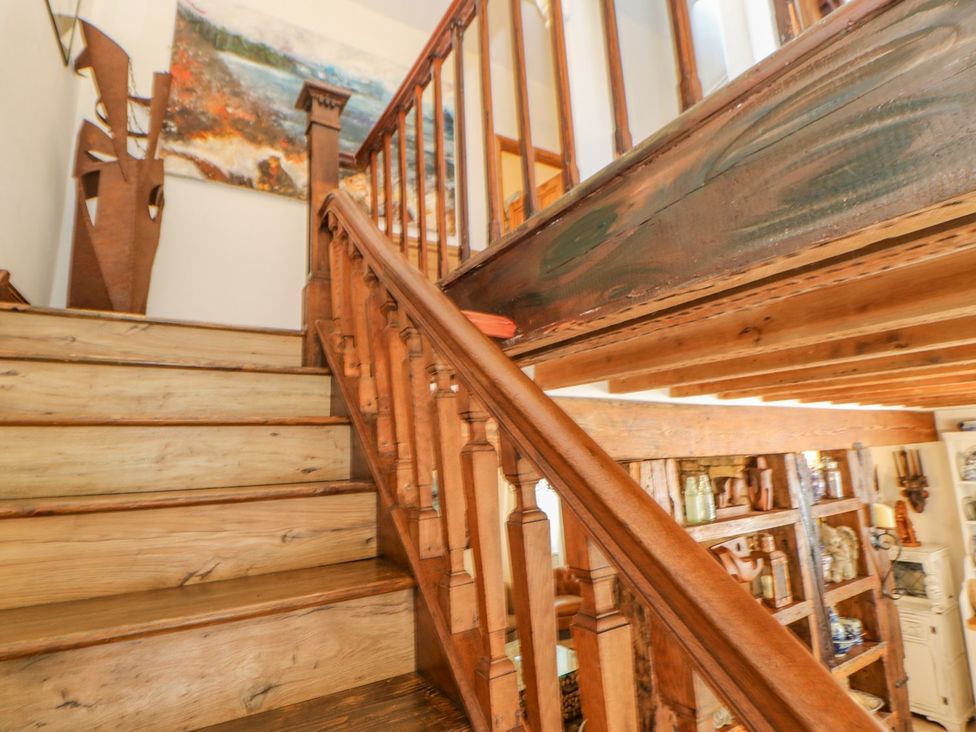 A wooden staircase with railing and an abstract painting on the wall at Shaftoe Mews in Haydon Bridge