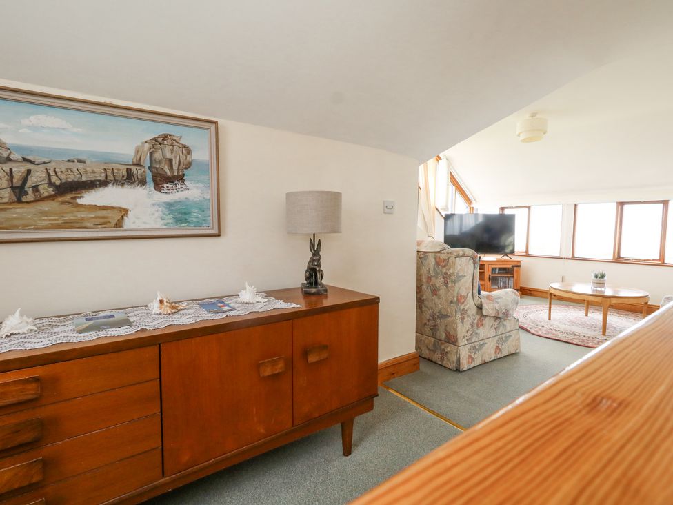 A sideboard with a lamp and seashells next to a living room with a TV armchair and coffee table at Old Higher Lighthouse Branscombe Lodge Portland Bill