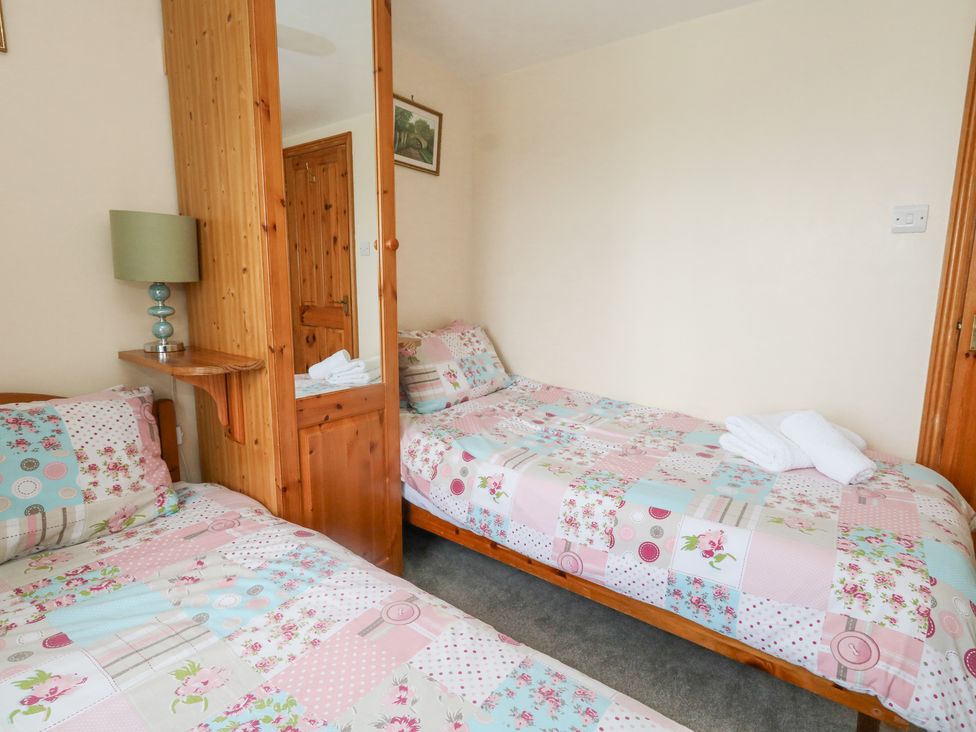 A bedroom with two single beds with patchwork quilts a wooden wardrobe with a mirror and a lamp on a small wall shelf at Old Higher Lighthouse Branscombe Lodge Portland Bill
