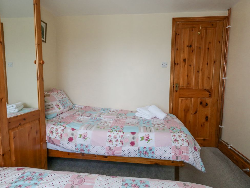 A bedroom with two single beds with patchwork quilts wooden wardrobe with mirror and wooden door at Old Higher Lighthouse Branscombe Lodge Portland Bill