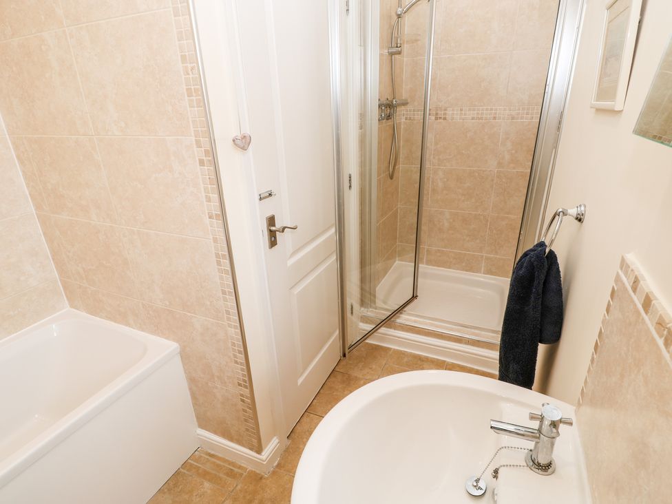A bathroom with a bathtub a shower cubicle and a sink at Driftwood Apartment in Amble-by-the-Sea