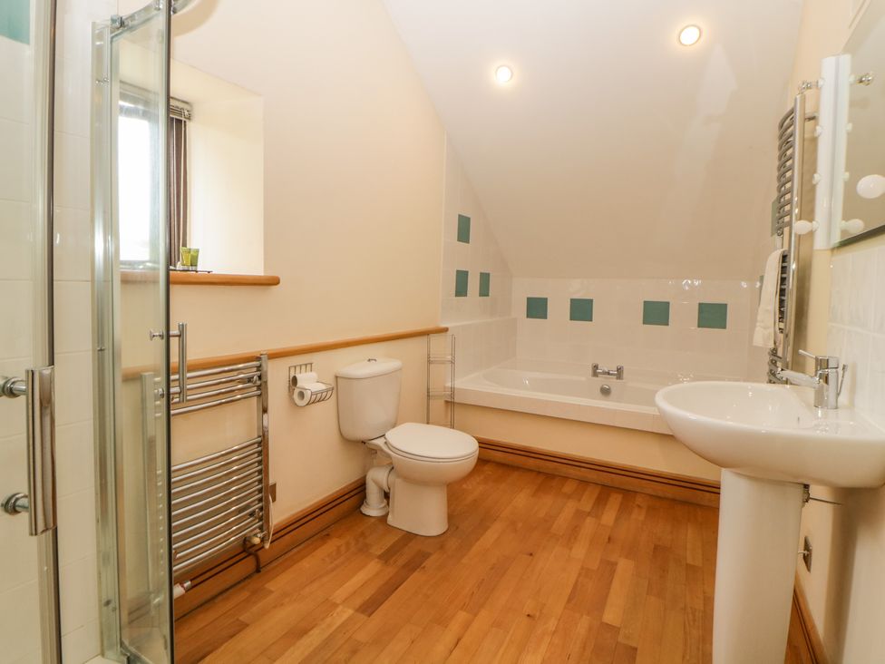 A bathroom with a bathtub a toilet a sink a glass shower enclosure and wooden flooring at Meader Barn Peter Tavy near Tavistock
