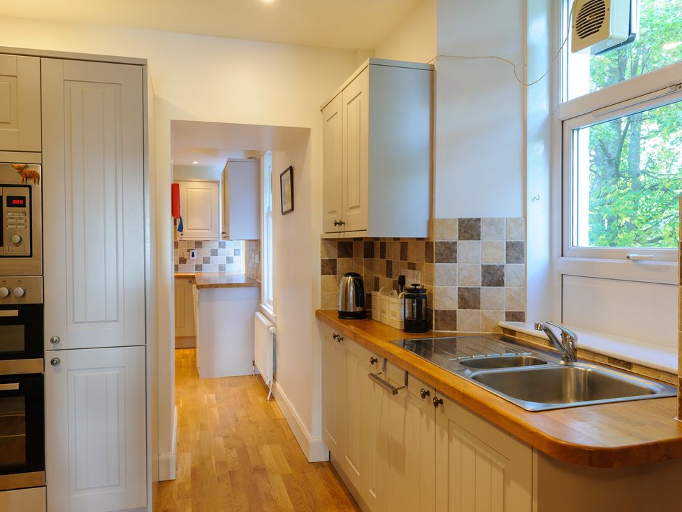 A kitchen with wooden countertops a double sink a kettle and cabinets by a window at Alvey House in Newtonmore