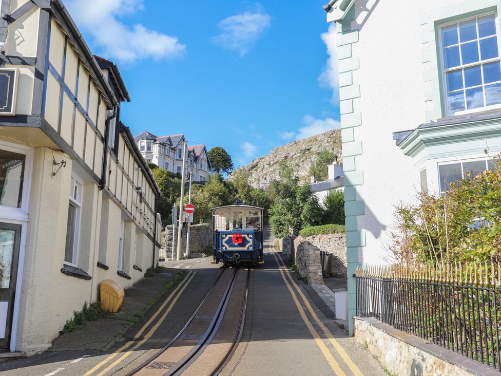 A blue and white tram on tracks between buildings on a street with double yellow lines at Pabo Lodge in Llandudno Junction near Llandudno