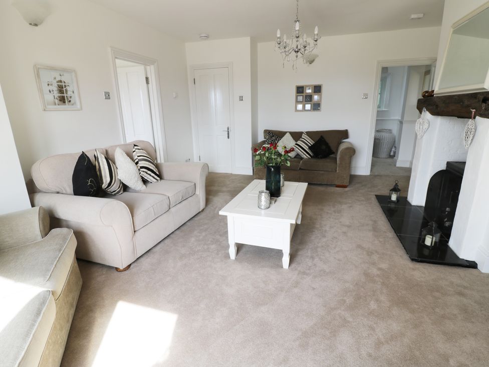 A living room with two sofas a white coffee table flowers and cushions at Hillview Cottage Knightwick near Worcester