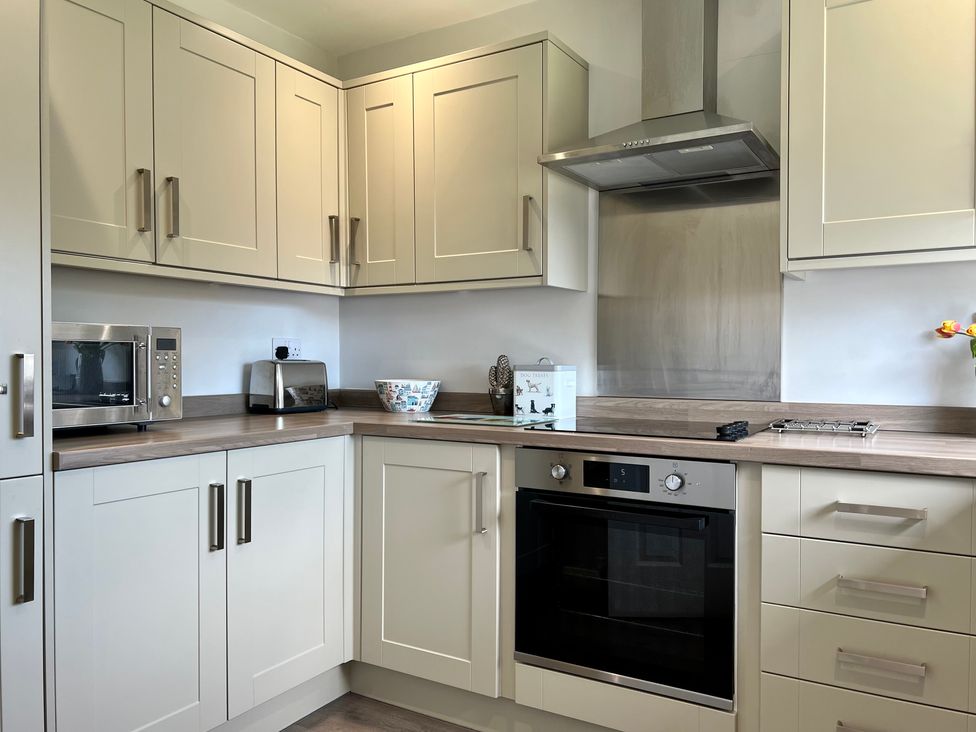 A kitchen with white cabinets a microwave toaster oven and stove at Araucaria House in Whitby
