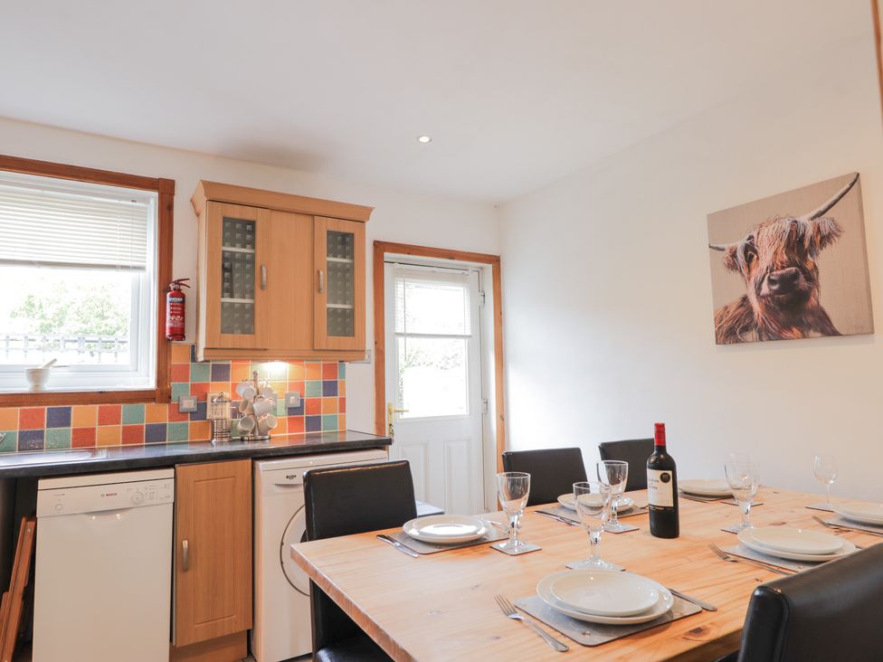 A kitchen with a wooden dining table set for six and colorful tiled backsplash at 2 Riverside in Foyers