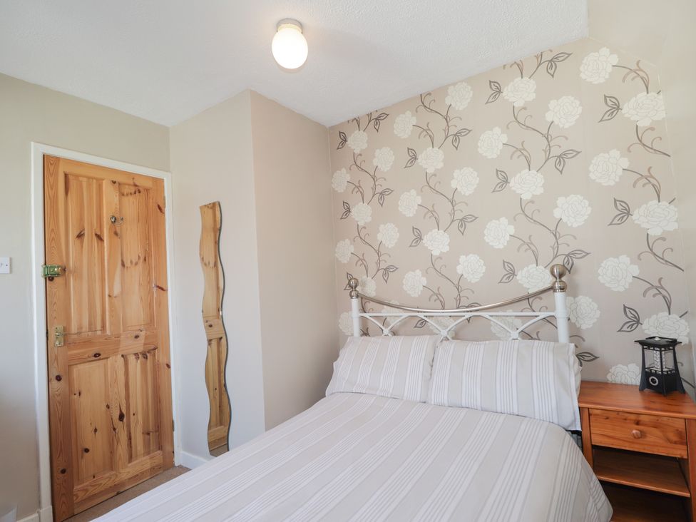 A bedroom with a bed striped bedding a wooden door a wall mirror and a nightstand at 2 Riverside in Foyers