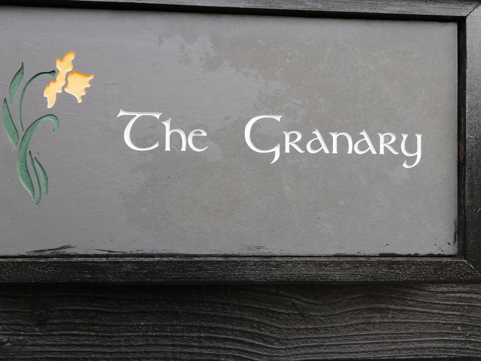 A sign with the words The Granary and a yellow flower on the left side at The Granary in Eardisley