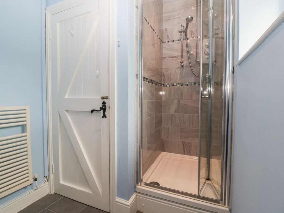 A bathroom with a glass shower enclosure and a white wooden door at The Pheasant Two in Raglan