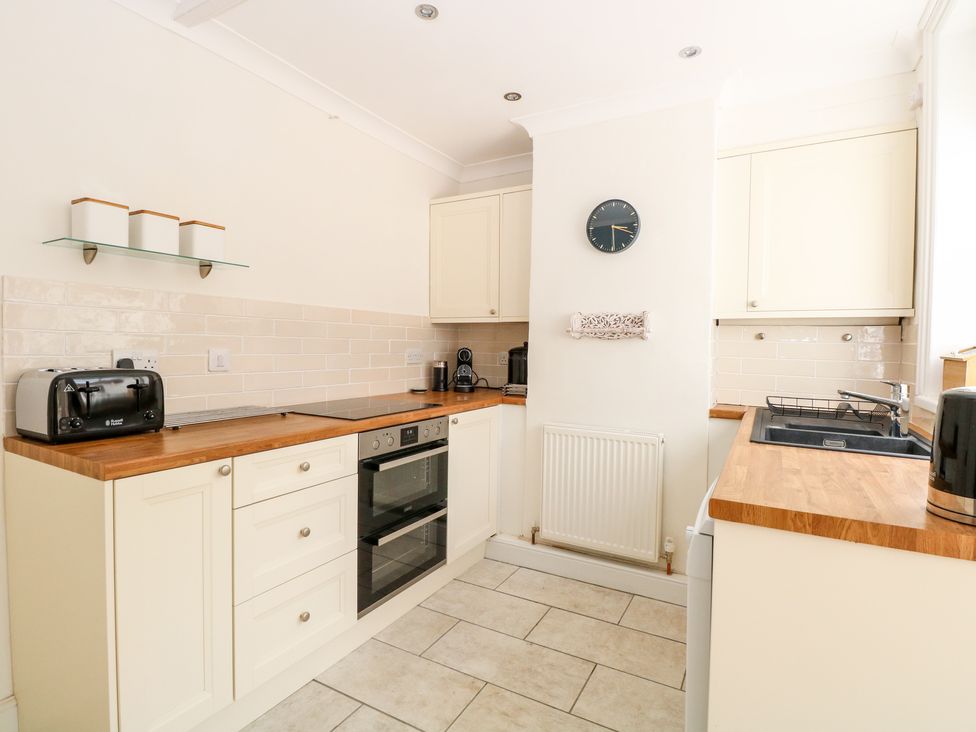 A kitchen with wooden countertops black appliances and cream cabinets at Springfield in Hempton near Fakenham