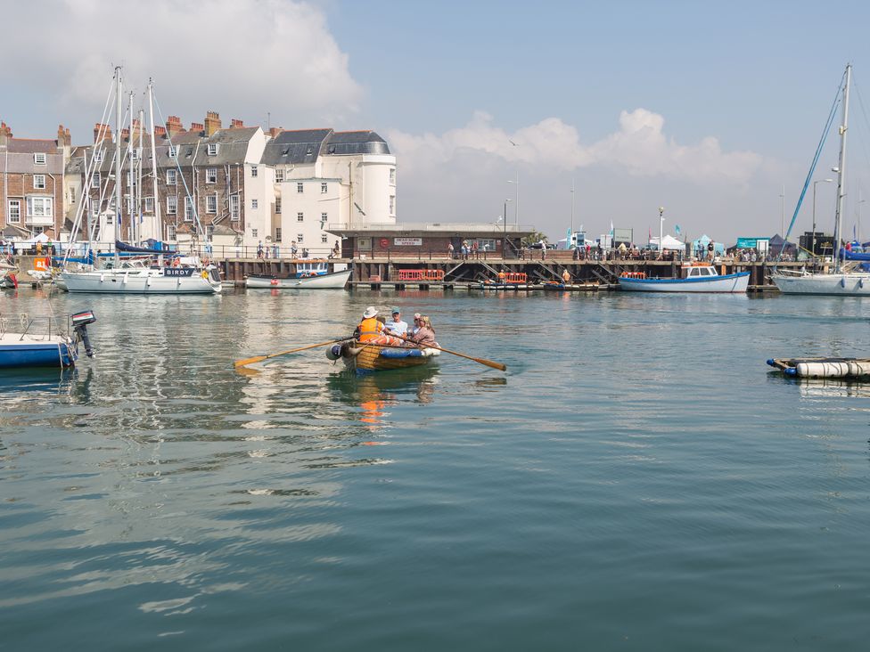 A harbor scene with people rowing a small boat and buildings in the background at Admirals Quarter Apartment 4 Weymouth